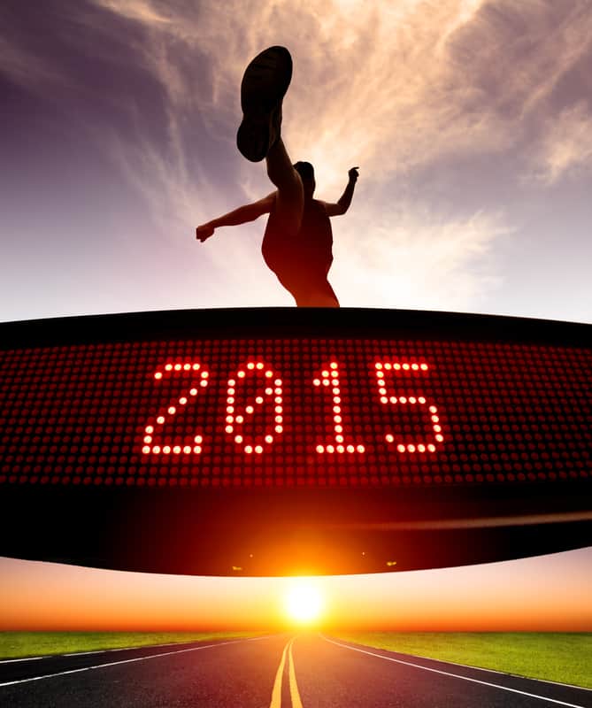 Silhouette of a person kicking toward a sky illuminated by the warm glow of a setting or rising sun. Below them is an electronic display reading "2015". The scene is set over a straight road and dramatic clouds.