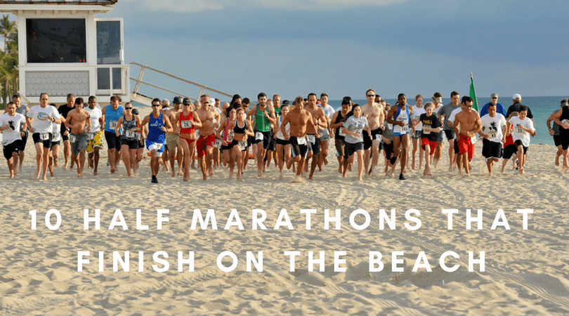 A group of runners on a beach is participating in a race. They are near a lifeguard station, with the ocean in the background. The text overlay reads, "10 Half Marathons That Finish On The Beach.