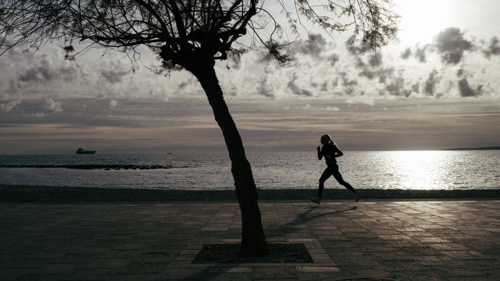 a solitary figure jogs along the sea promenade of portixol in palma de mallorca. 