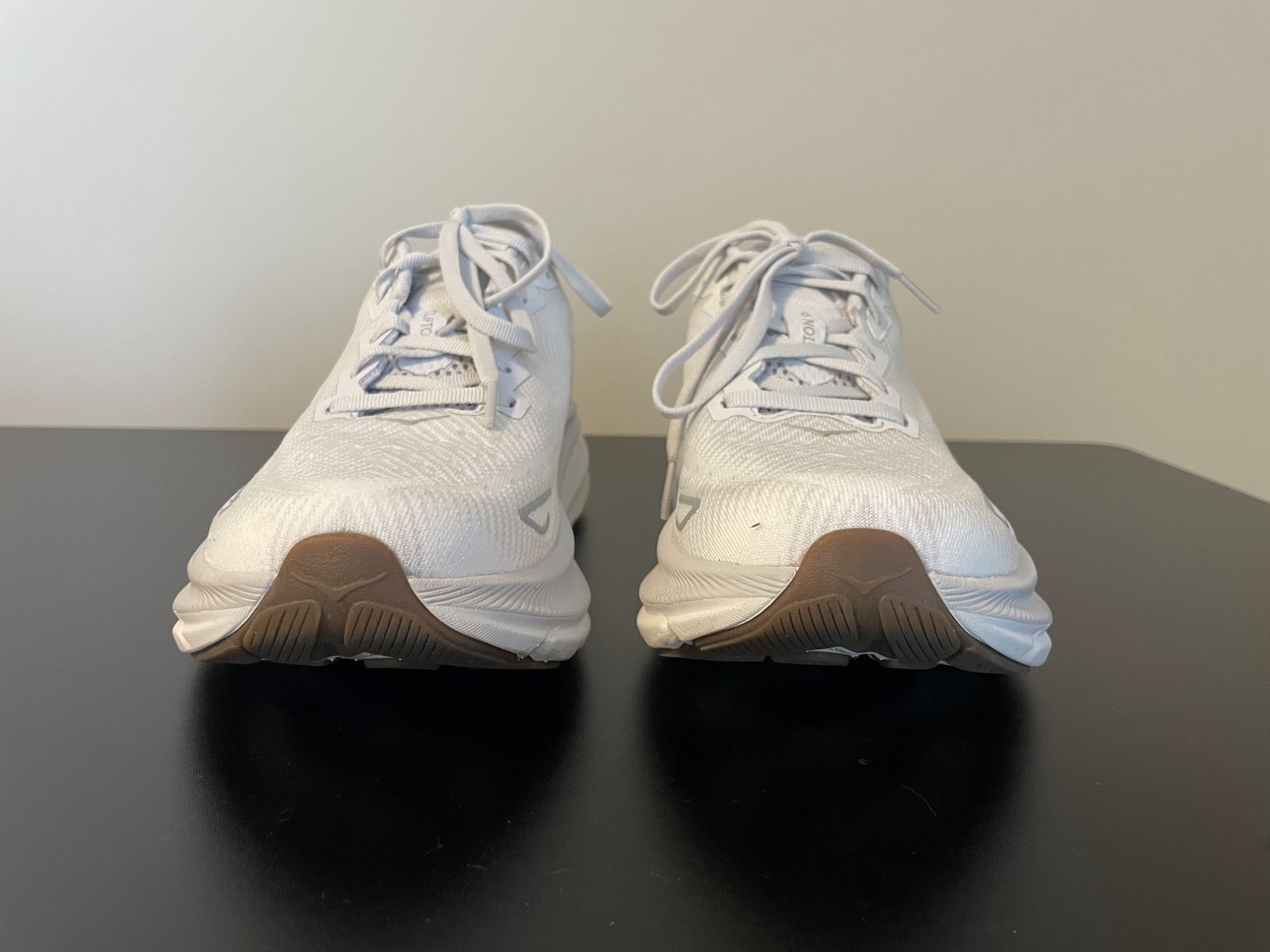 The front view of a pair of white Hoka Clifton 9 running shoes.