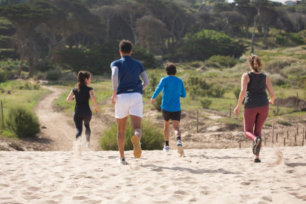 A group of friends running, doing Fartlek training in the sand.