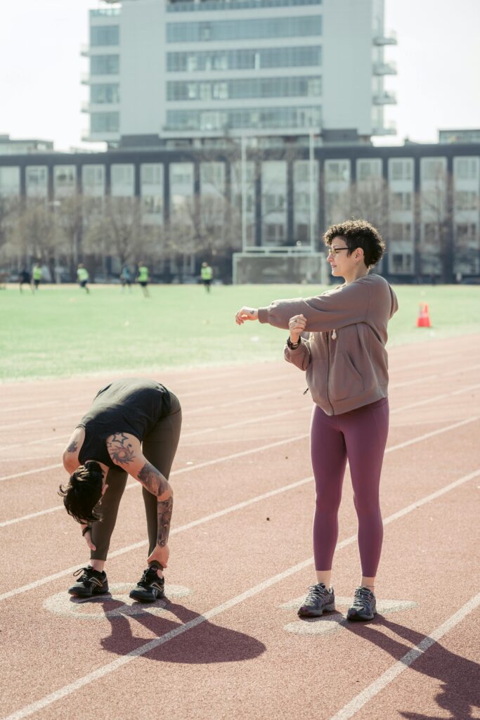 Two runners stretching on a track before a workout like fartlek training